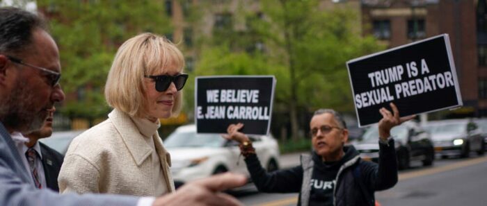 While a protester holds up signs, E. Jean Carroll arrives to federal court in New York, Thursday, April 27, 2023. Carroll began testifying Wednesday in the trial of her federal lawsuit. The writer has told a jury that Donald Trump raped her after she accompanied him into a luxury department store fitting room in 1996.