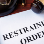 A gavel on top of a paper that reads "restraining order."