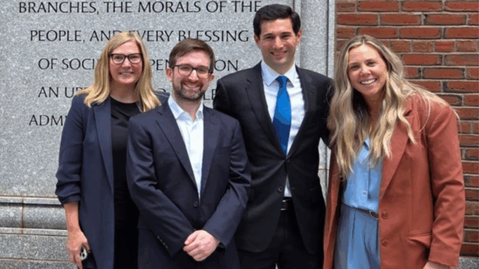 Four people smiling together outside a courthouse.